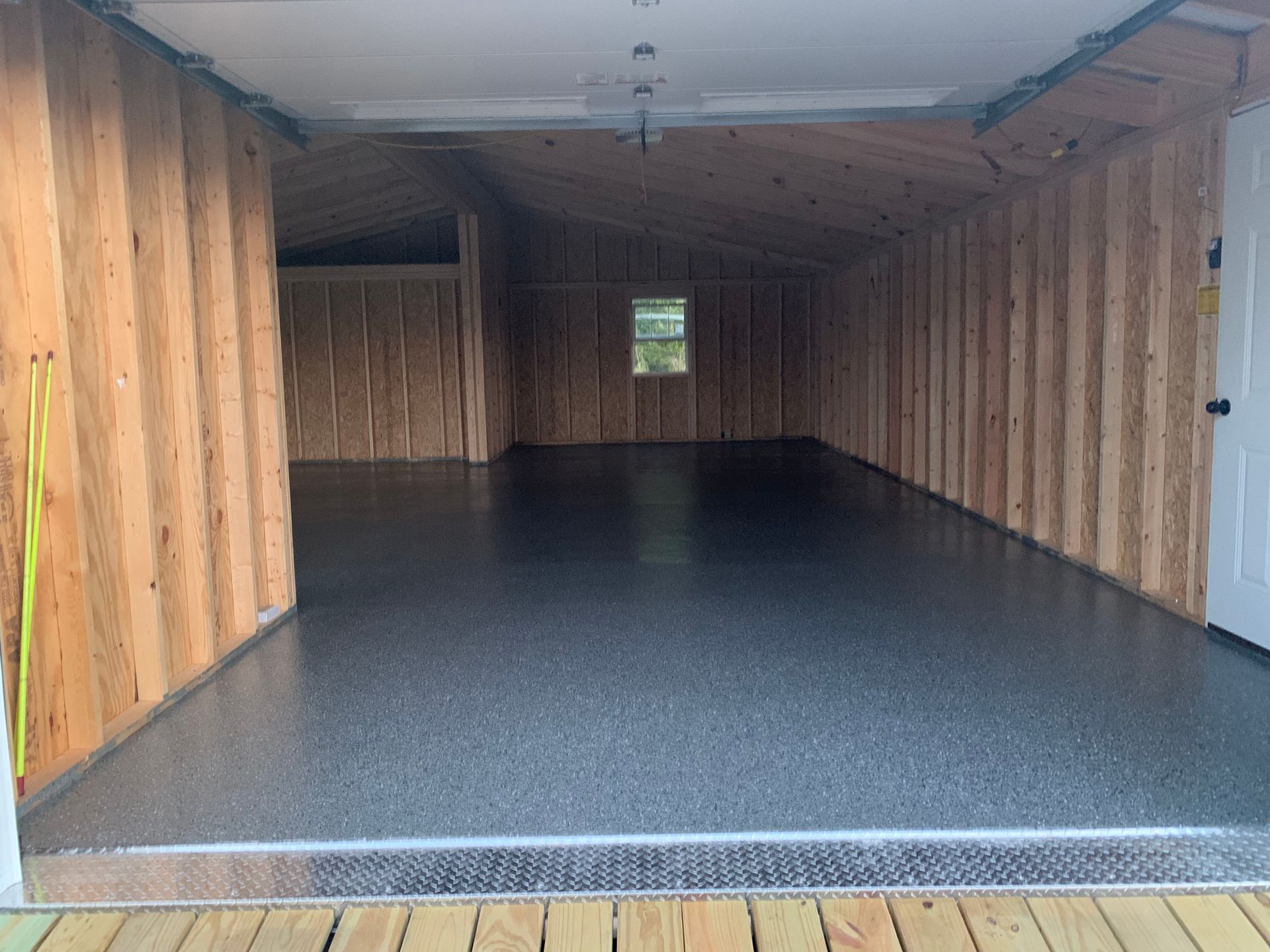 Empty wooden shed with dark floor and a small window at the back.