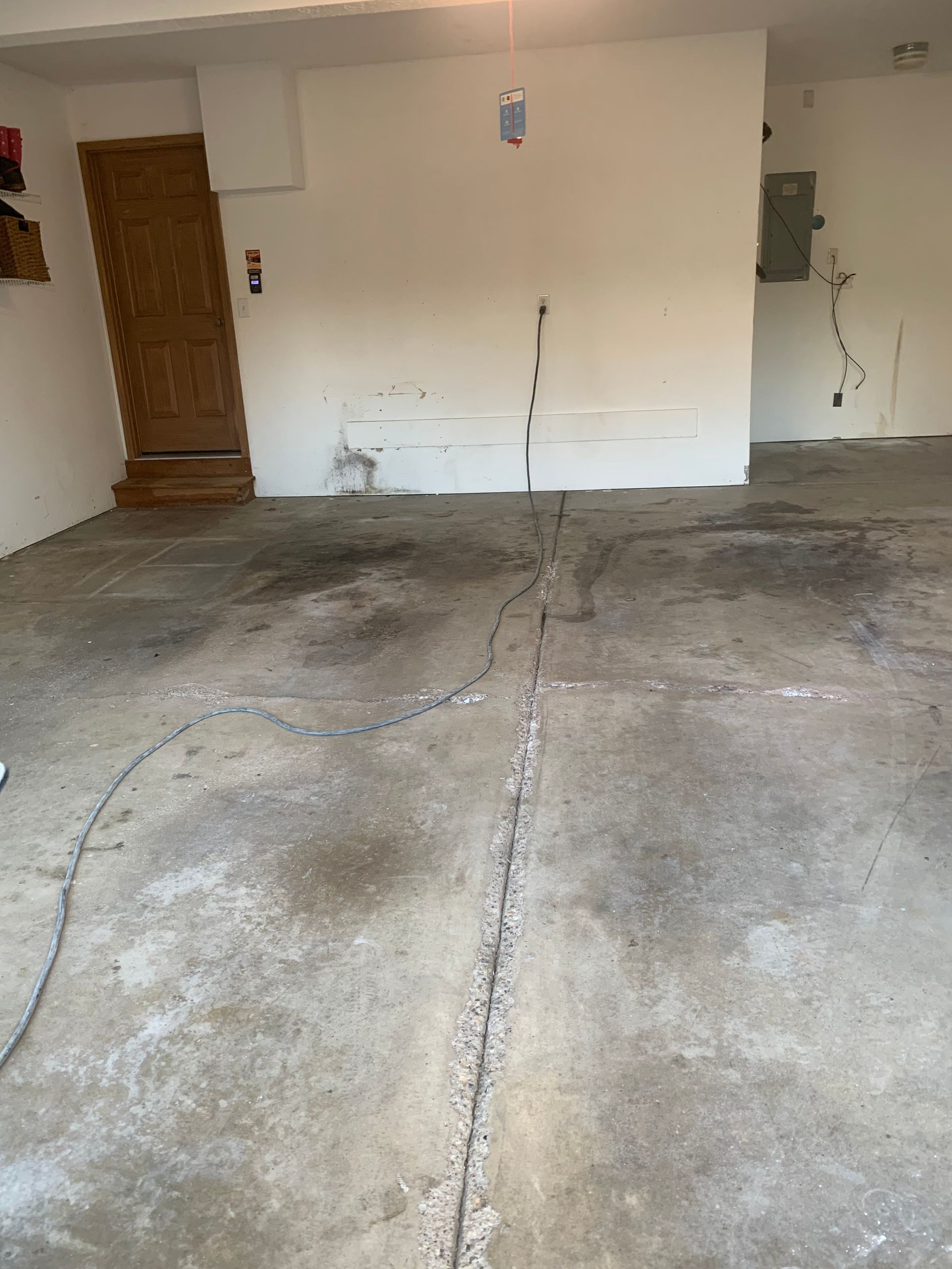 Empty garage with concrete floor cracks and a wooden door on the left wall