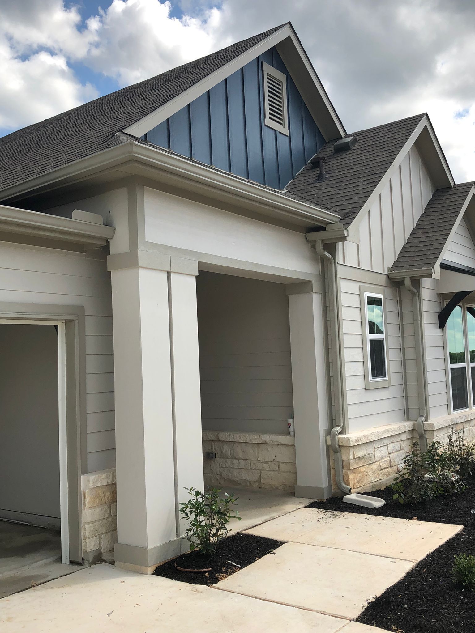 Exterior of a new house with blue accents, a gray roof, and a covered porch.