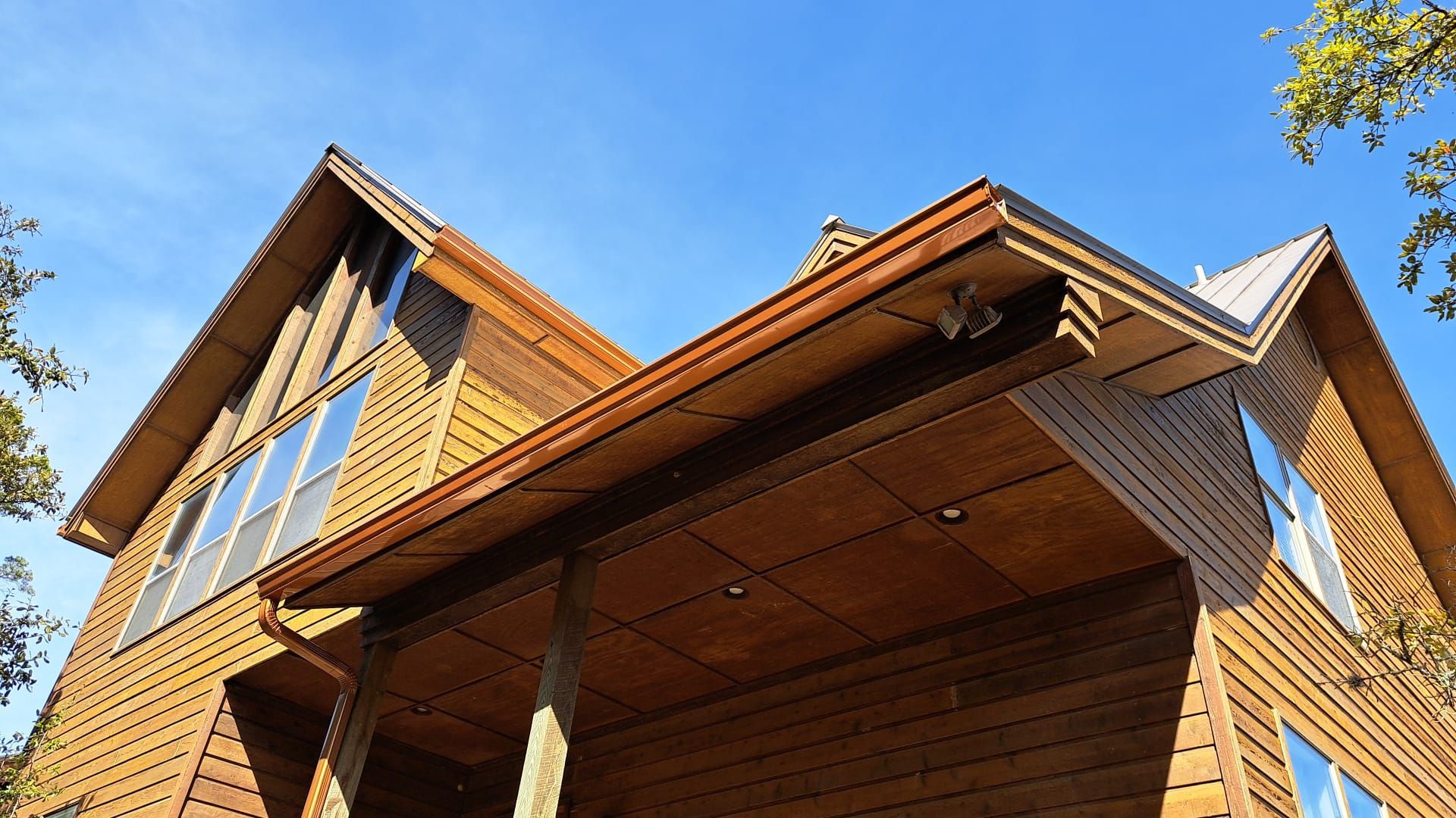 Wooden house exterior with a porch, under a clear blue sky.