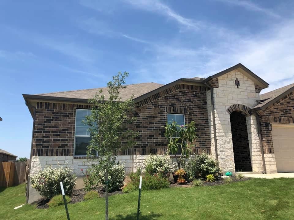 House with brick and stone exterior, green lawn, blue sky.