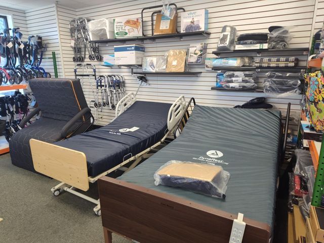 A showroom displays adjustable hospital beds and medical supplies on shelves.