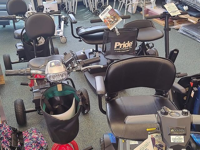 Scooters in a store, black seats, handle bars, some with baskets and bags.