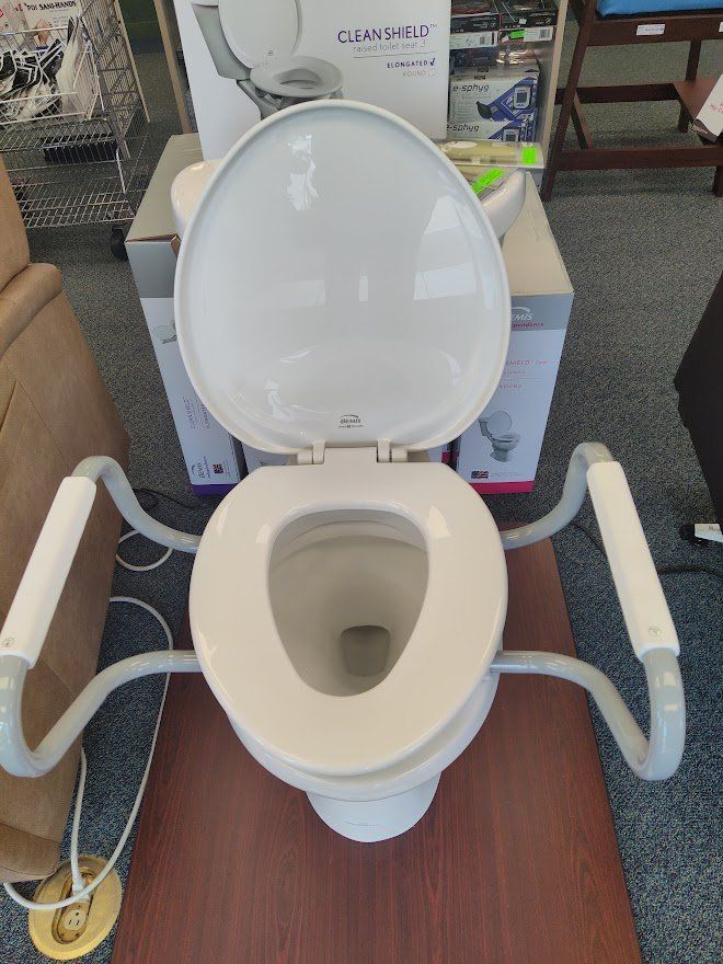 Raised toilet seat with armrests in a store.