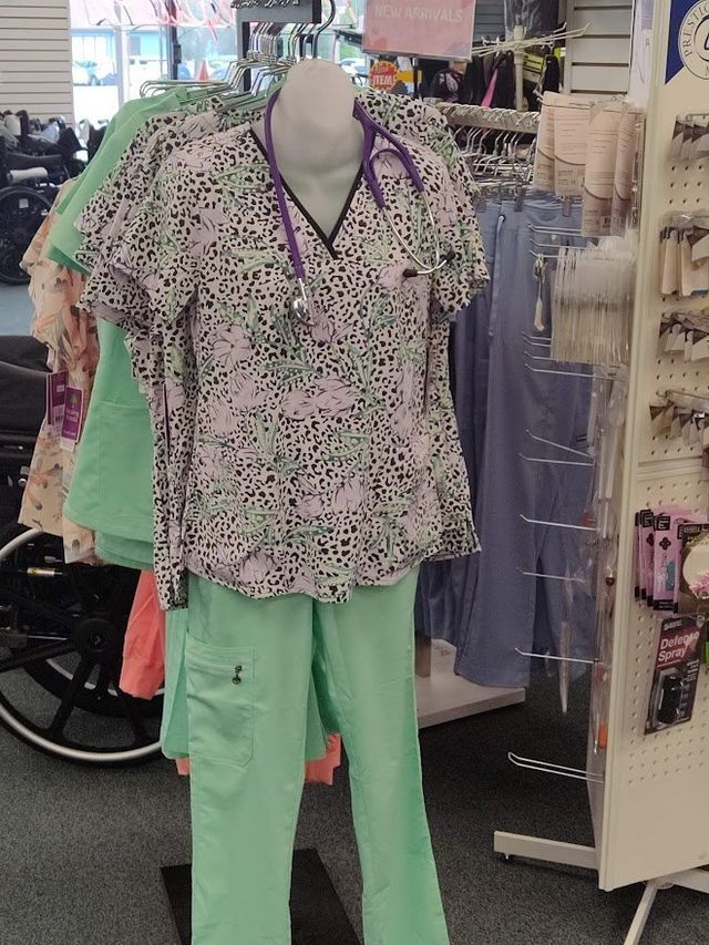Mannequin in medical scrubs, with a purple stethoscope, displayed in a store. Green pants and patterned top.