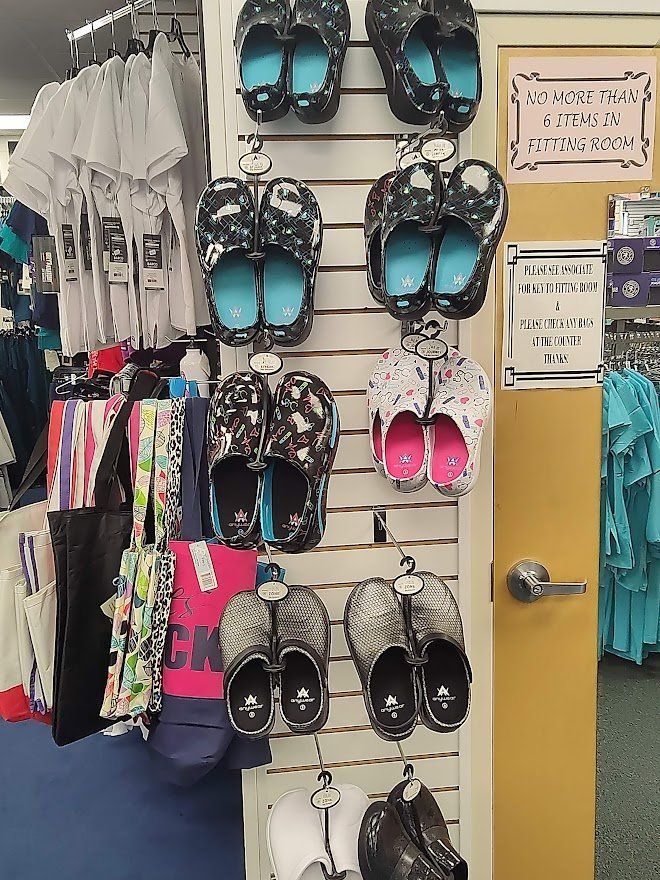 Shoes and shirts displayed in a store. Several pairs of shoes on a wall rack, with various designs and colors.