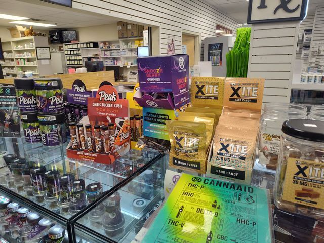 Inside a dispensary, displays of cannabis products like edibles and infused snacks are shown.