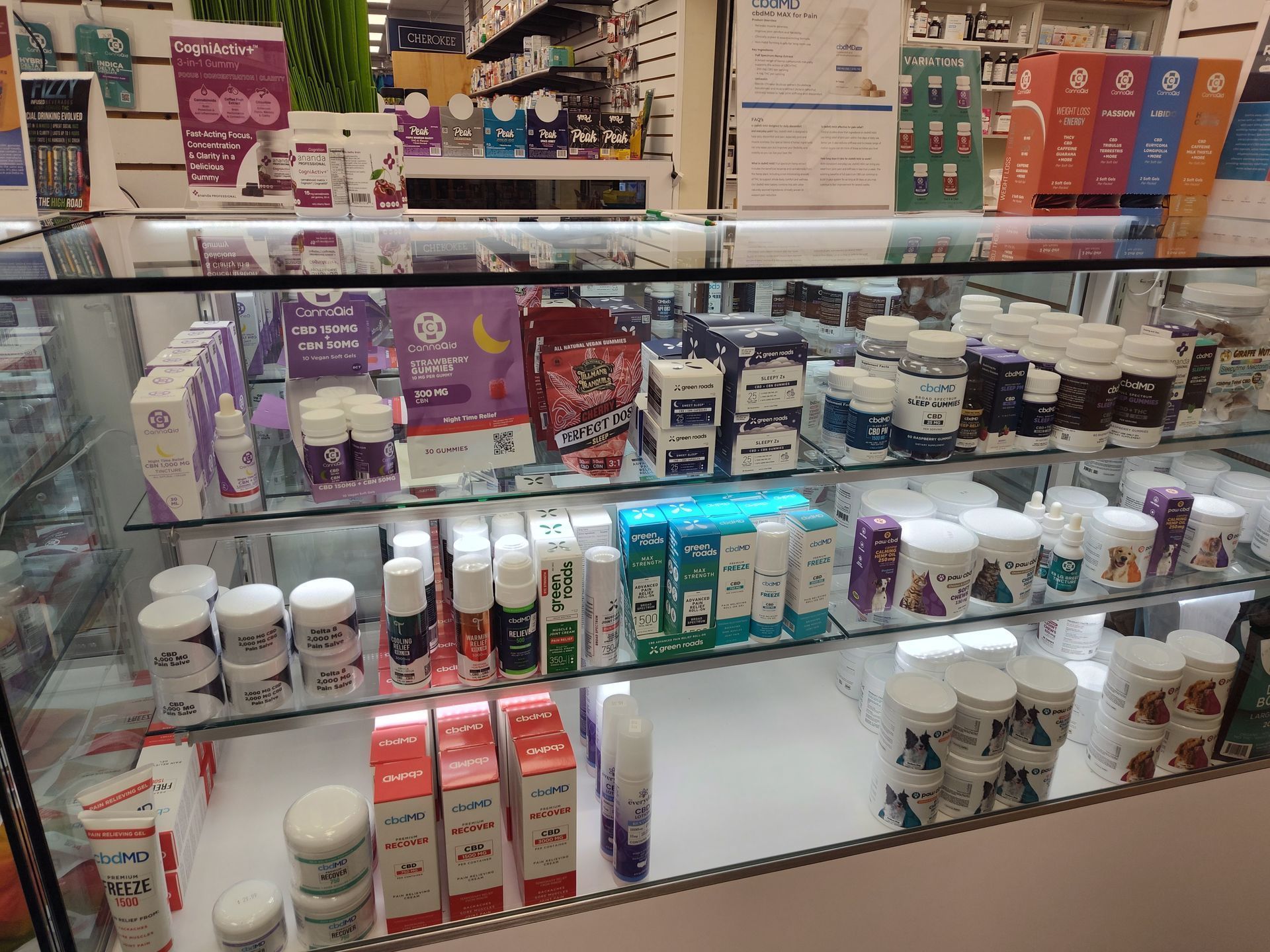Glass display case in a store, filled with various products in white, blue, red, and purple packaging.