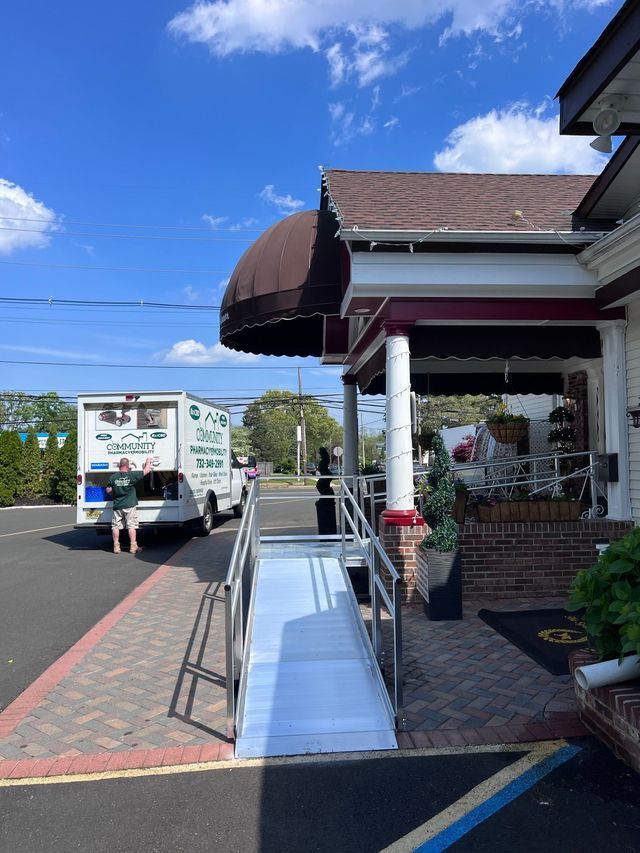 A building with a ramp leading to the entrance. A white truck is parked nearby.