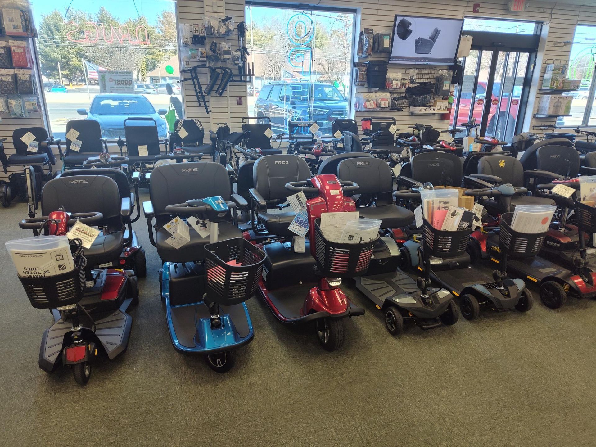 Mobility scooters displayed in a store, various colors, lined up.