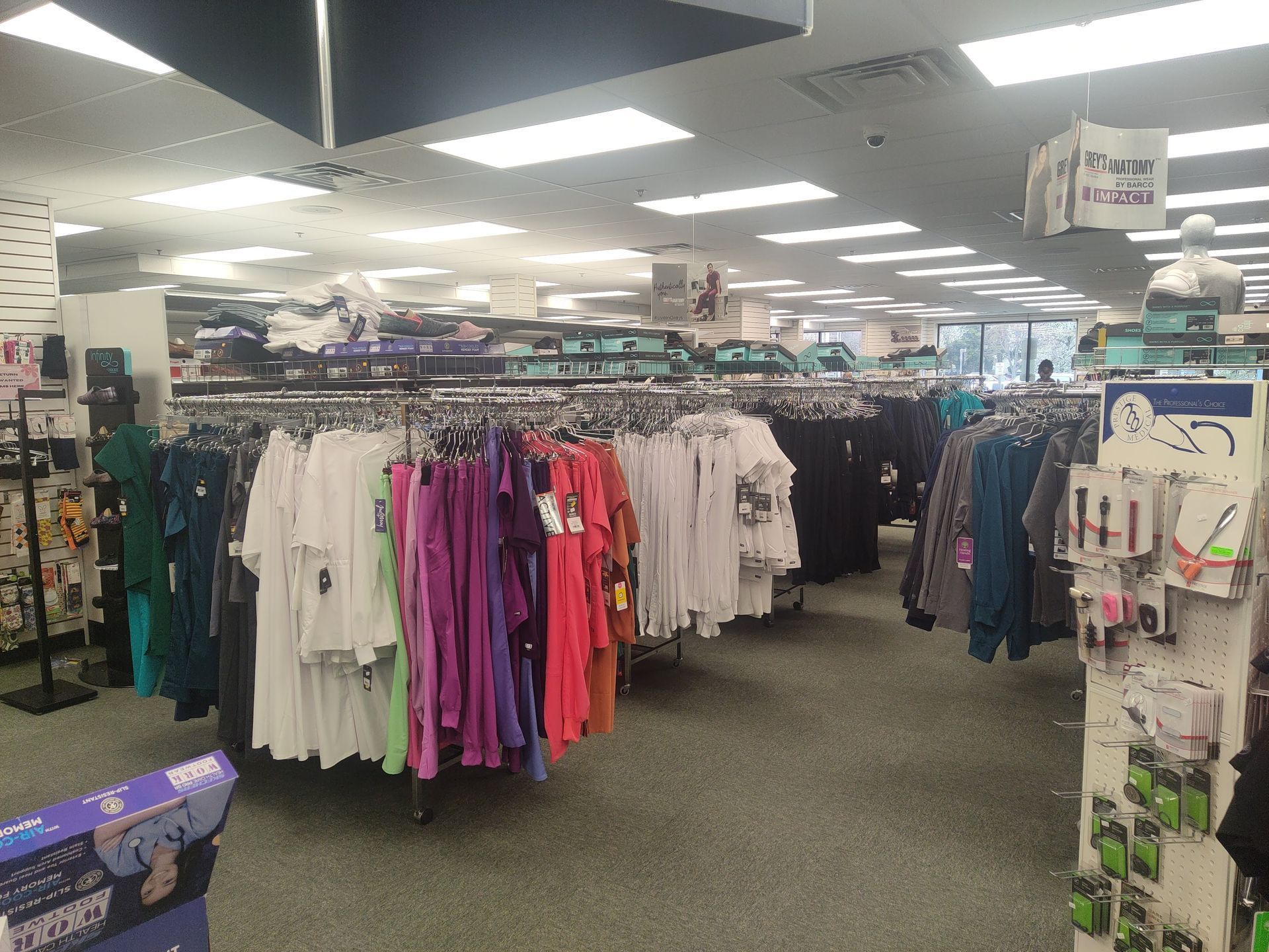 Clothing store interior with clothing racks, various colors, and overhead lighting.