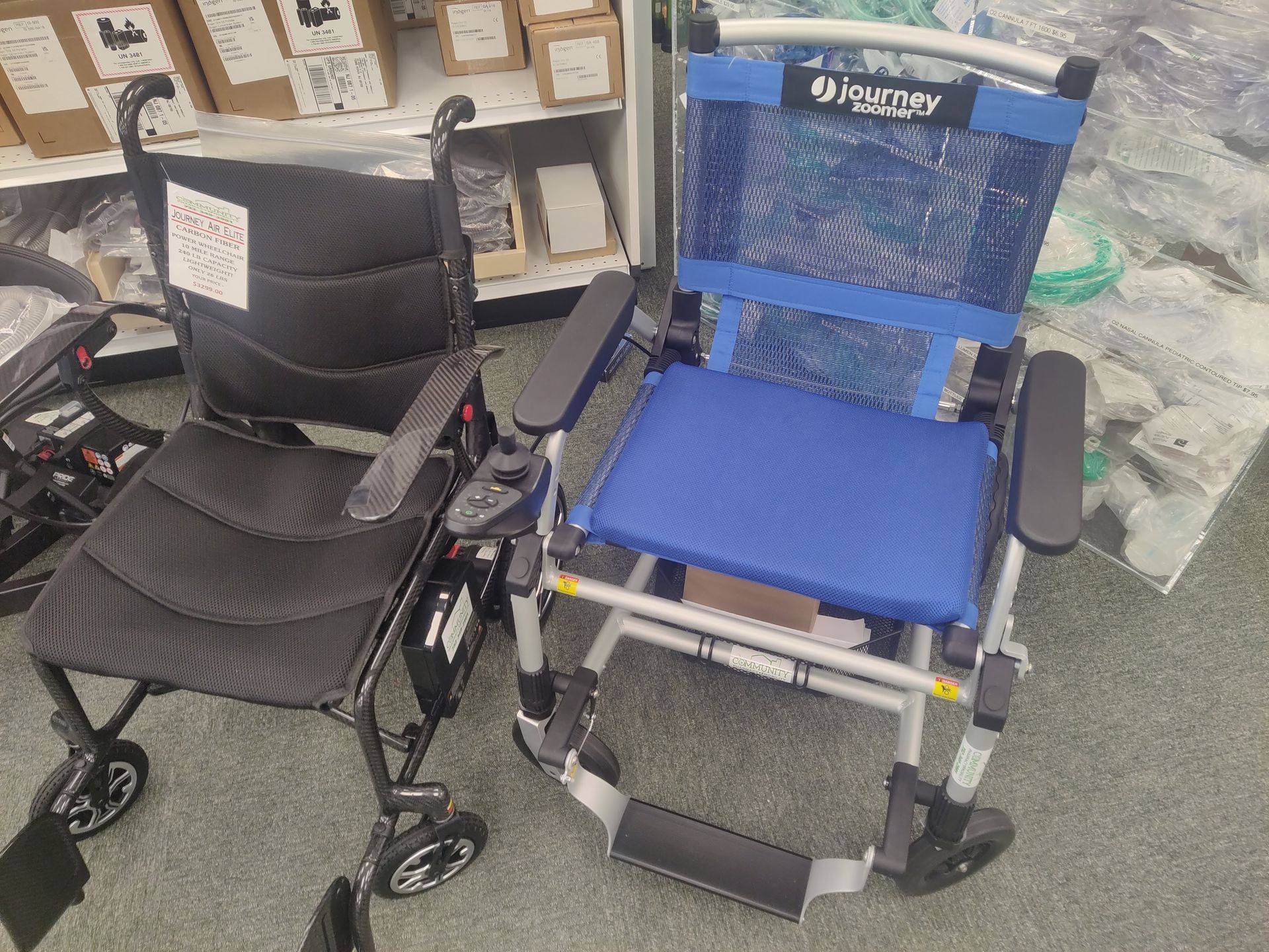Two wheelchairs, one black and one blue, side-by-side on a gray floor inside a store.