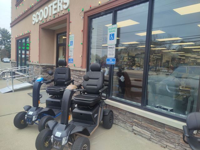 Two mobility scooters parked outside a store named 