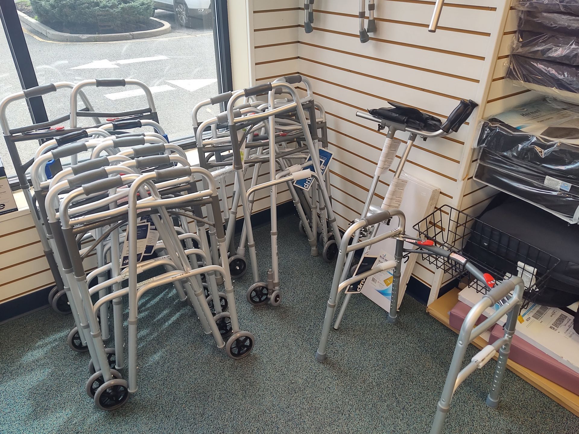 Walkers for sale inside a store. Several folded walkers are against a wall with a window.