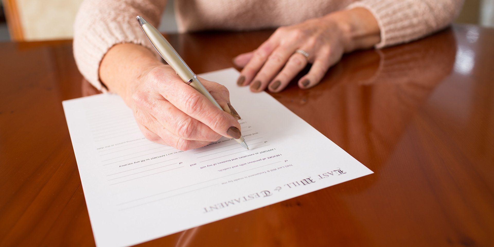 A woman is writing on a piece of paper with a pen.
