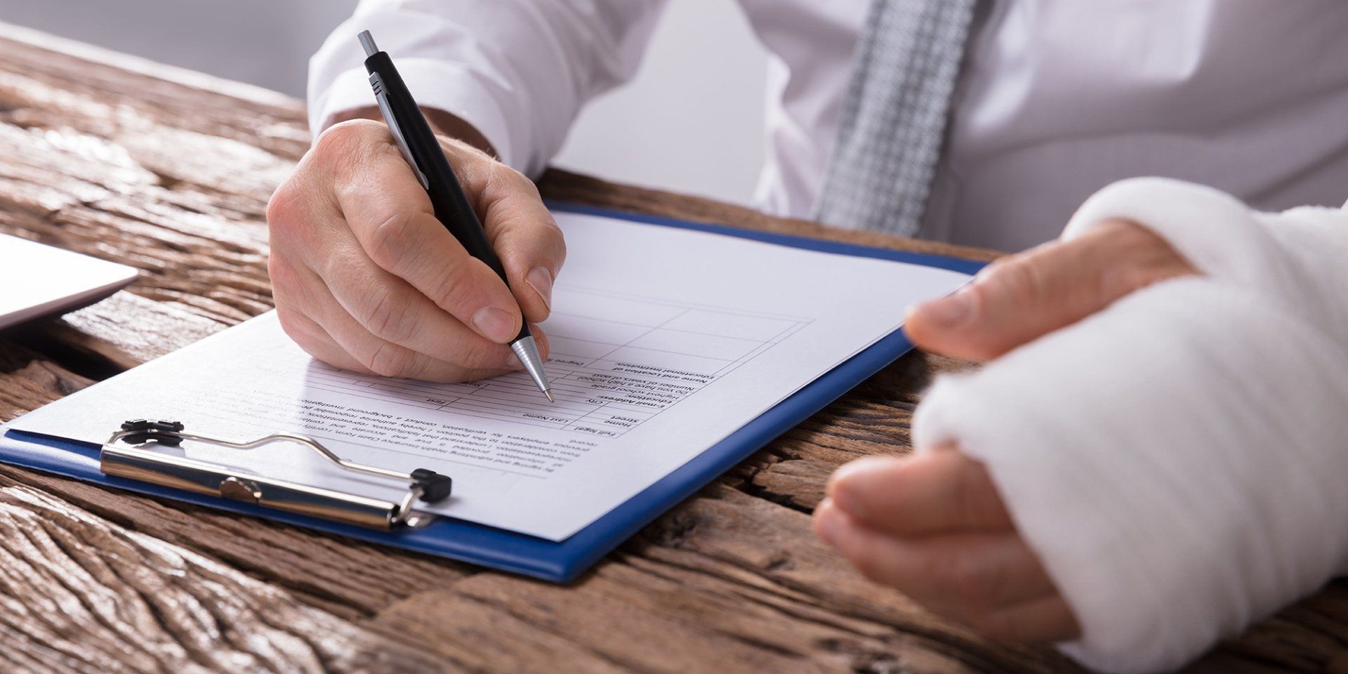 A person with a broken arm is writing on a clipboard.