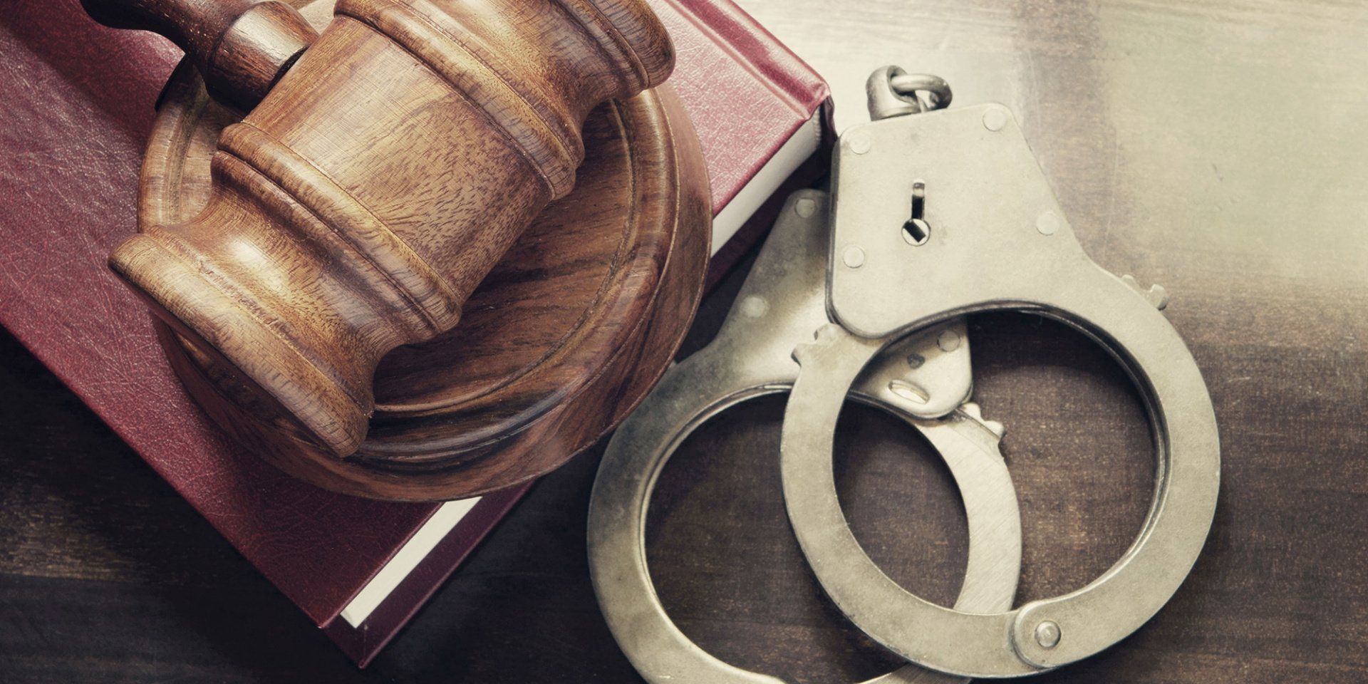 A wooden gavel and handcuffs are sitting on top of a book.