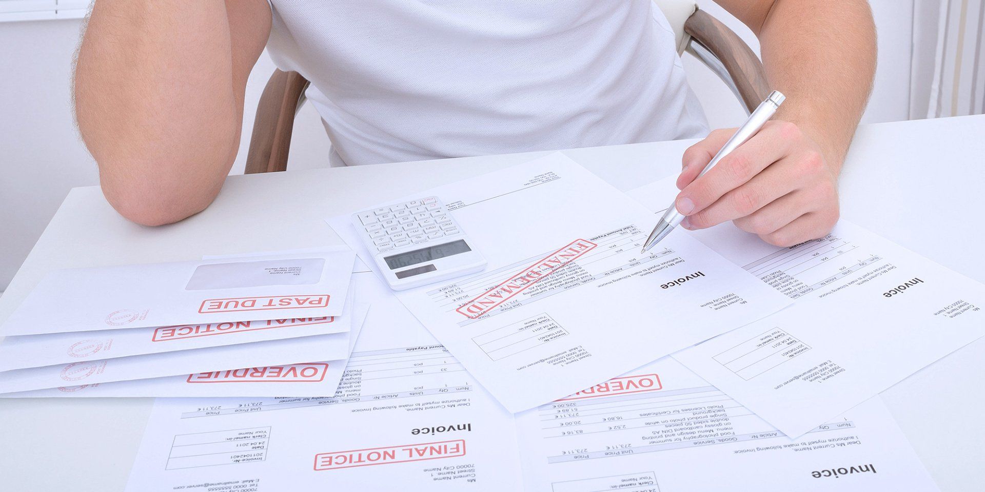 A man is sitting at a table writing on a piece of paper.