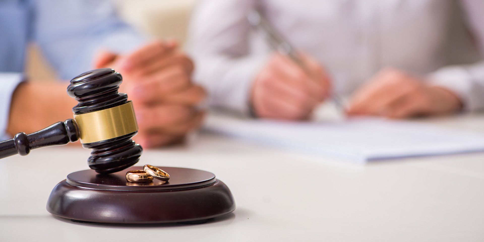 A judge 's gavel with a pair of wedding rings on it.