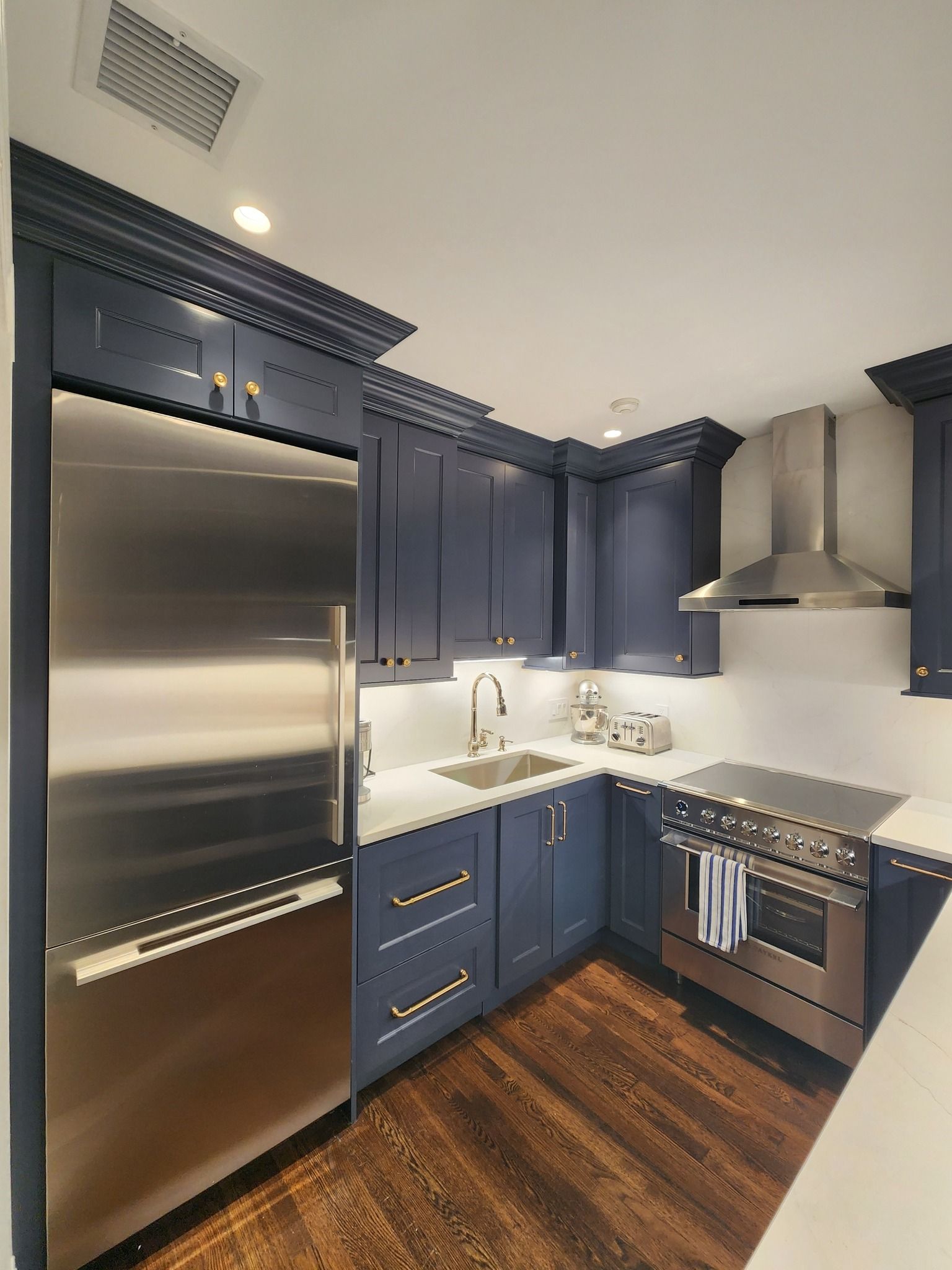 a kitchen with dark blue cabinets and stainless steel appliances