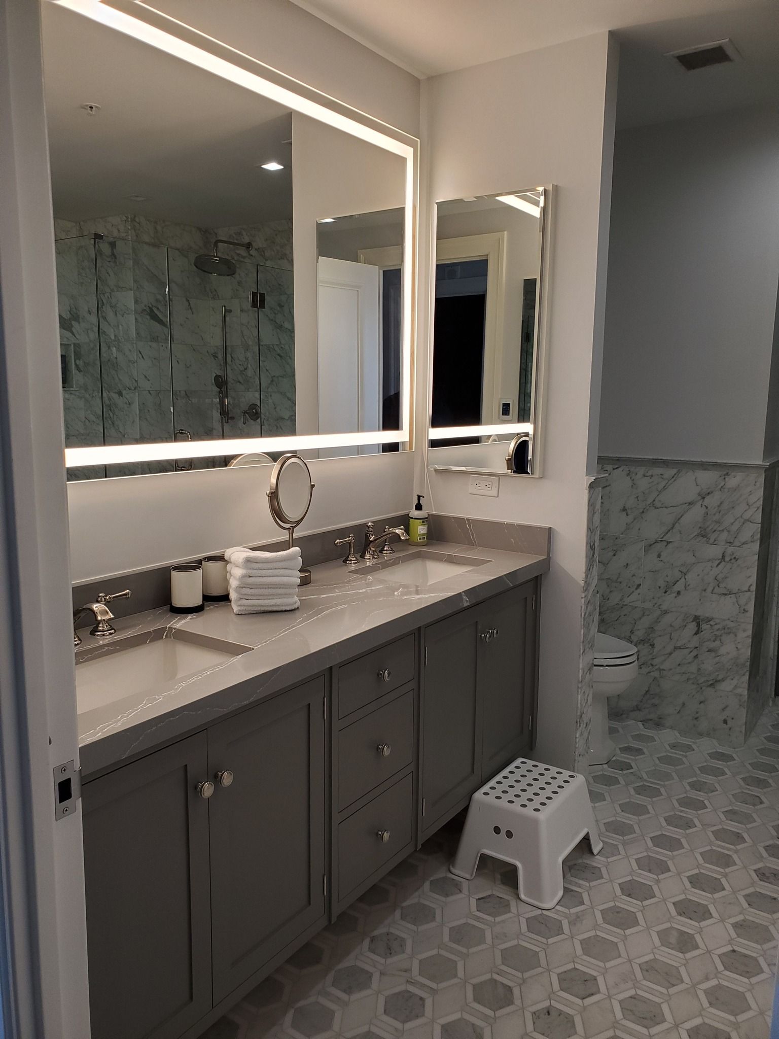 a bathroom with two sinks, a mirror, and a step stool