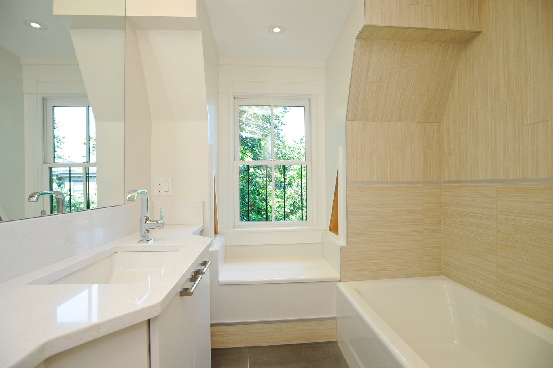 a bright, spacious bathroom with a sink, tub, mirror, and window