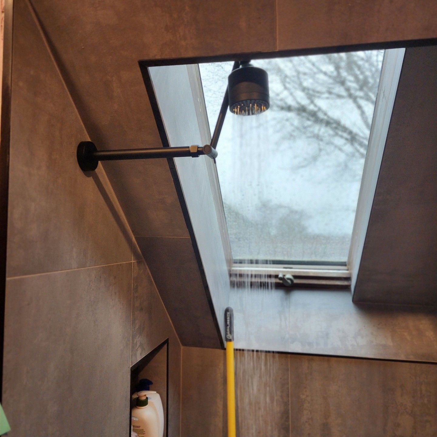 a bathroom with a skylight and a shower head