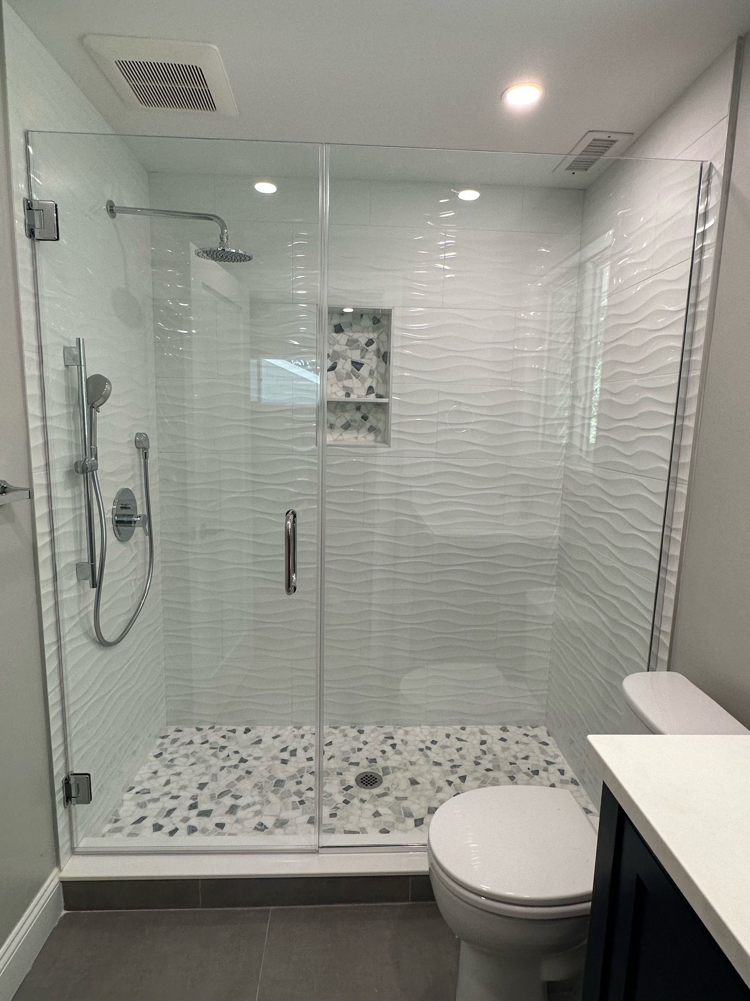 a bathroom with a walk-in shower, toilet, and sink