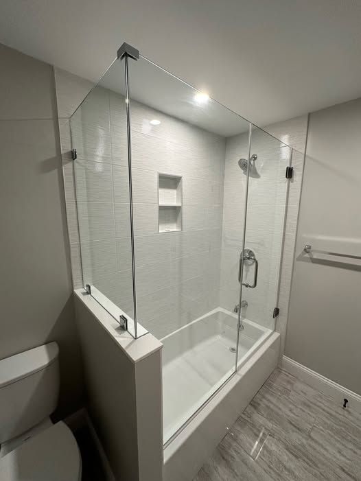 a bathroom with a bathtub, a toilet, and a glass shower door