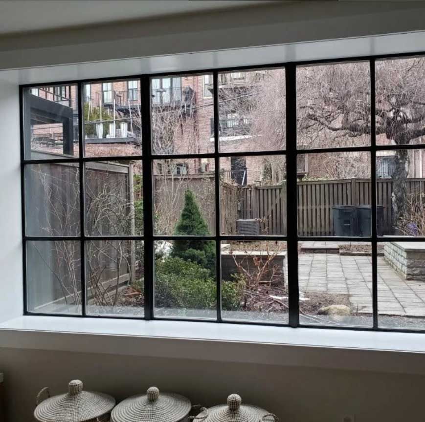 a large window with a view of a garden and a fence