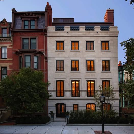 a brownstone building with a lot of windows is lit up at night