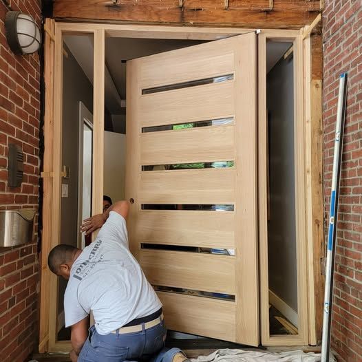 a man wearing a white shirt working on a wooden door