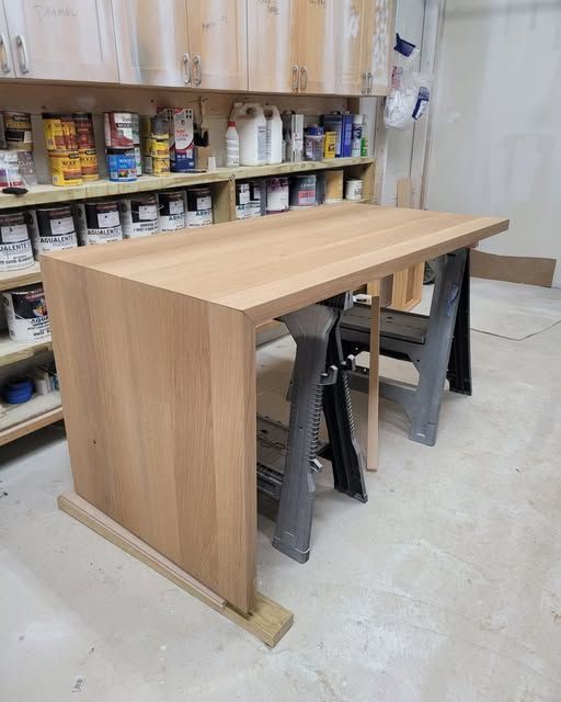 a wooden table next to a shelf full of paint