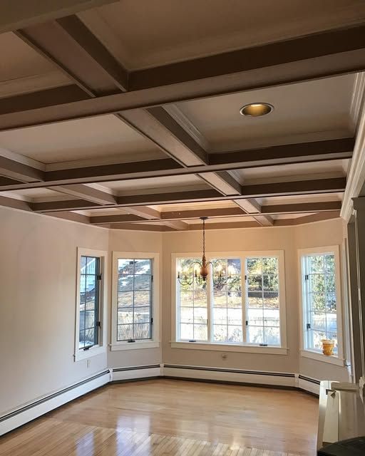 a living room with a coffered ceiling and lots of windows