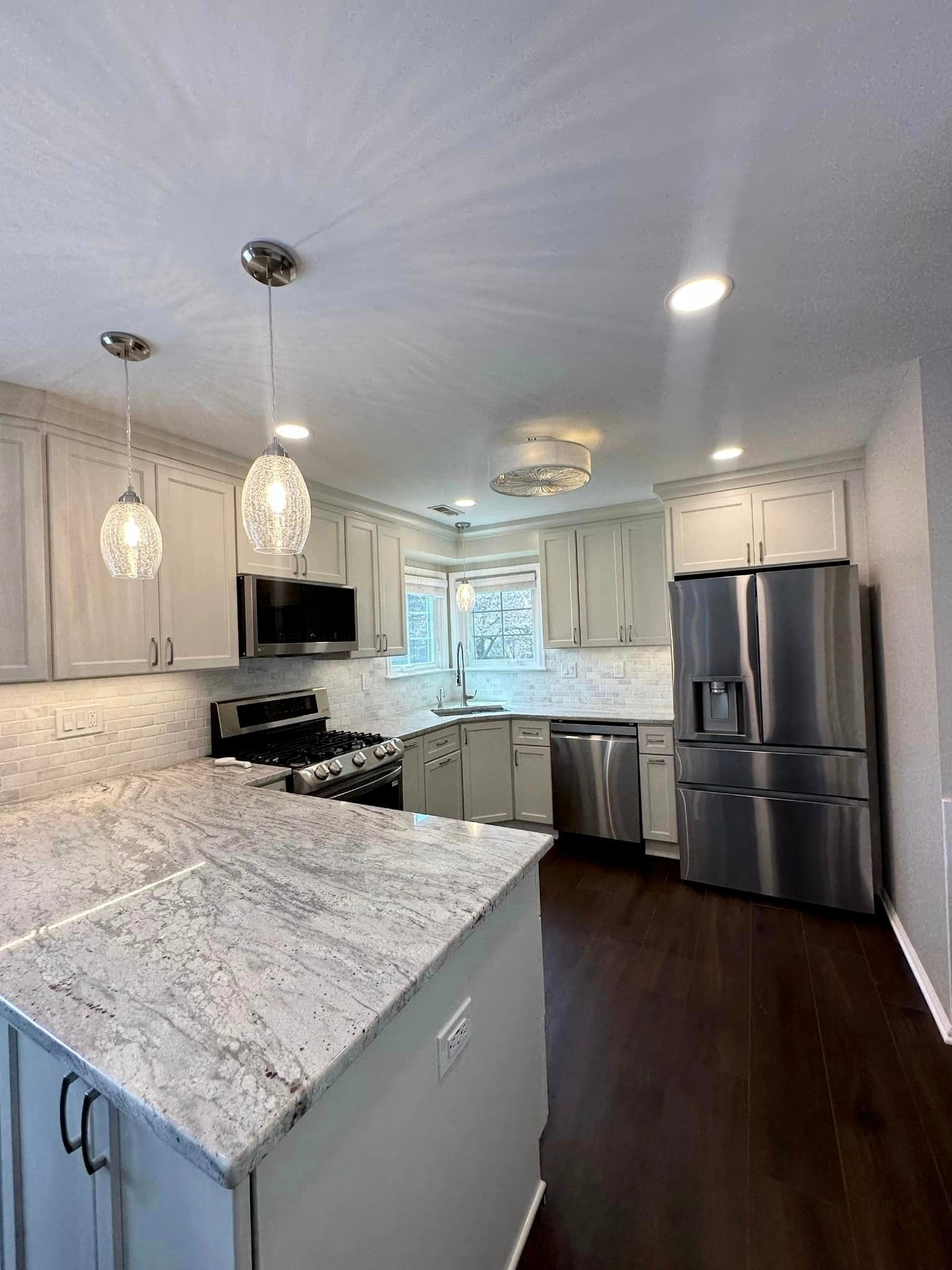 A kitchen with granite counter tops, stainless steel appliances, and white cabinets.