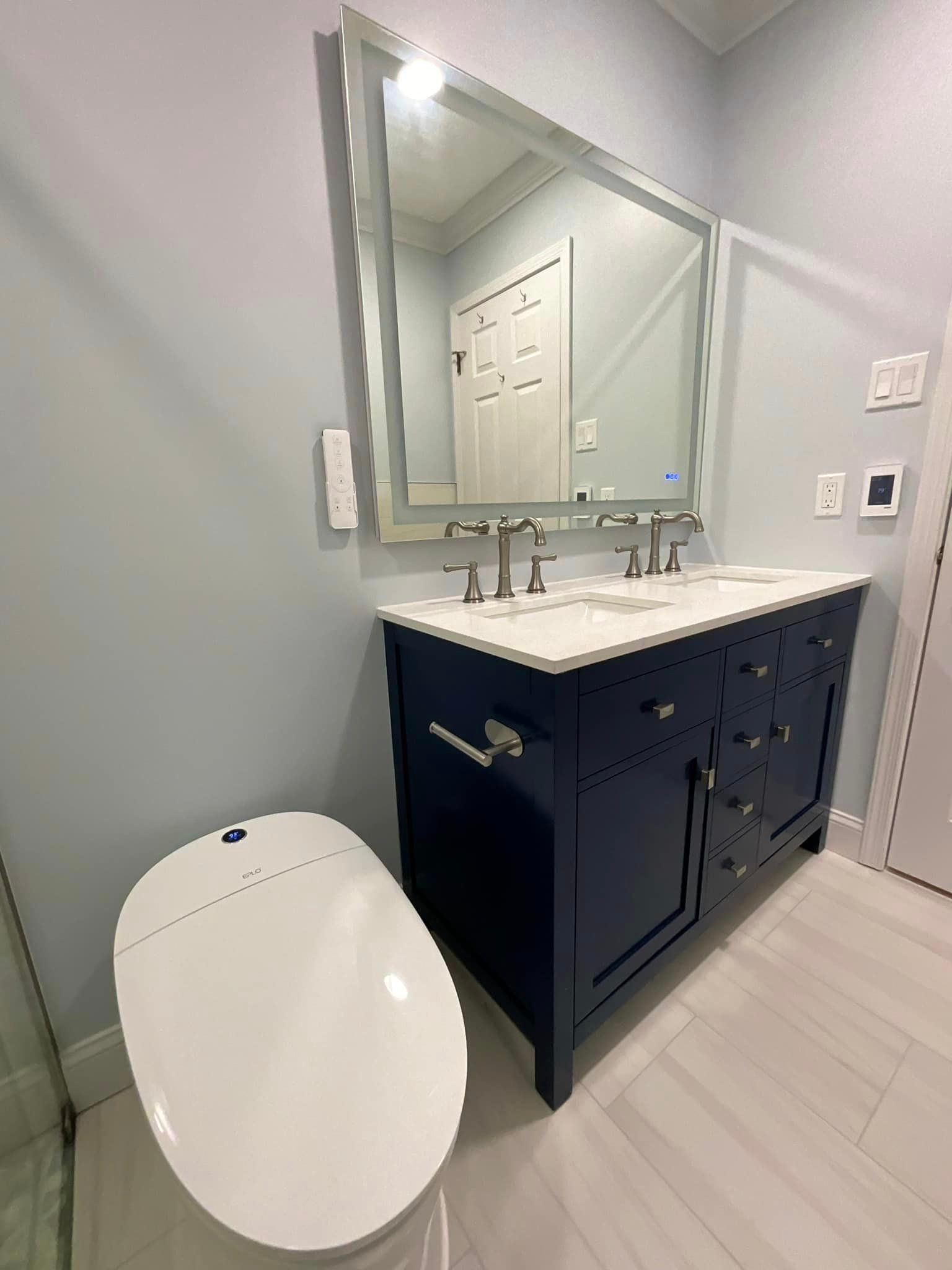 A bathroom with a toilet, sink, mirror and vanity.