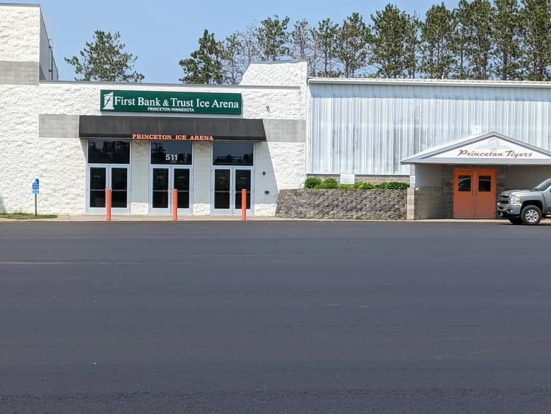 Exterior view of a commercial building with a bank and adjacent space. Bright sunshine.