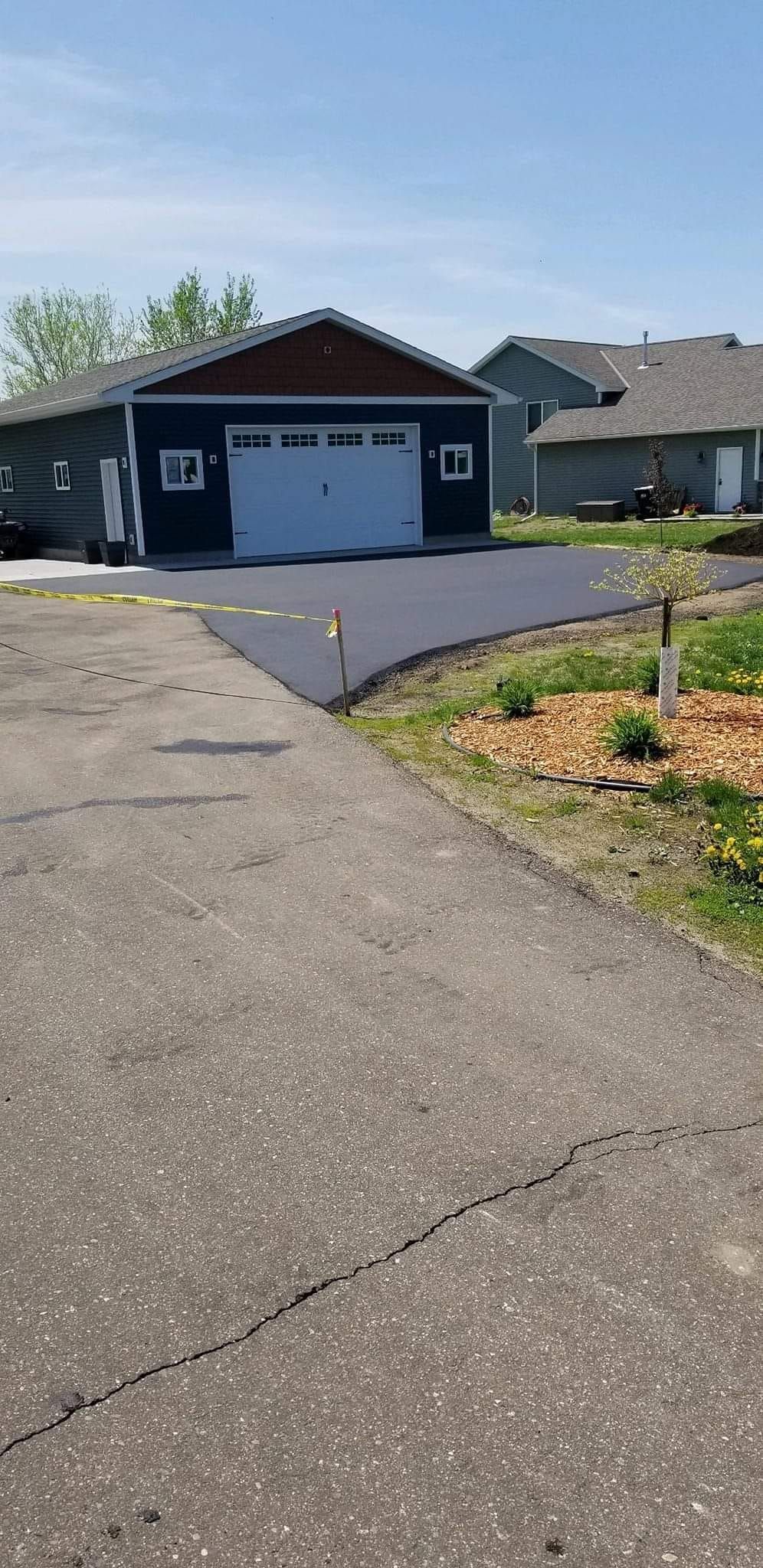 A paved driveway leads to a dark blue garage with a white door.