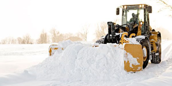 A snow plow is clearing snow from a road.
