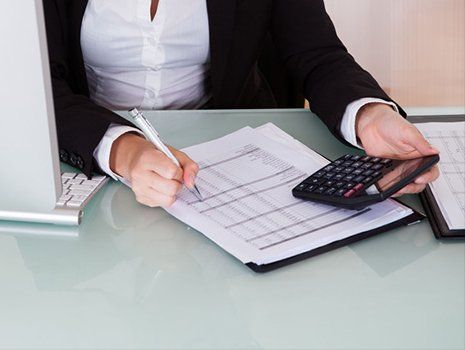 Accountant writing on document with calculator