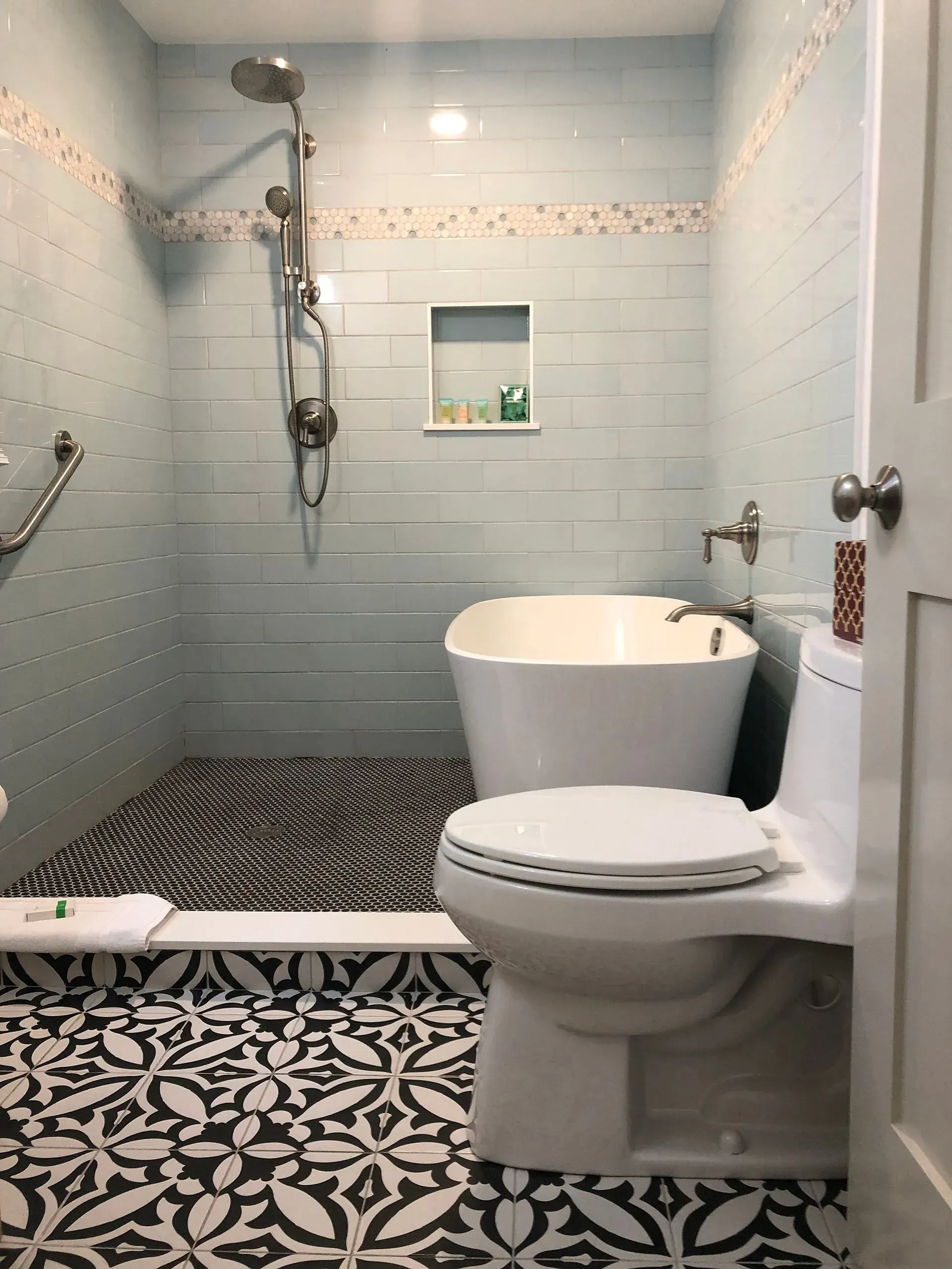 Bathroom with blue tiled walls, bathtub, toilet, and black/white patterned floor.