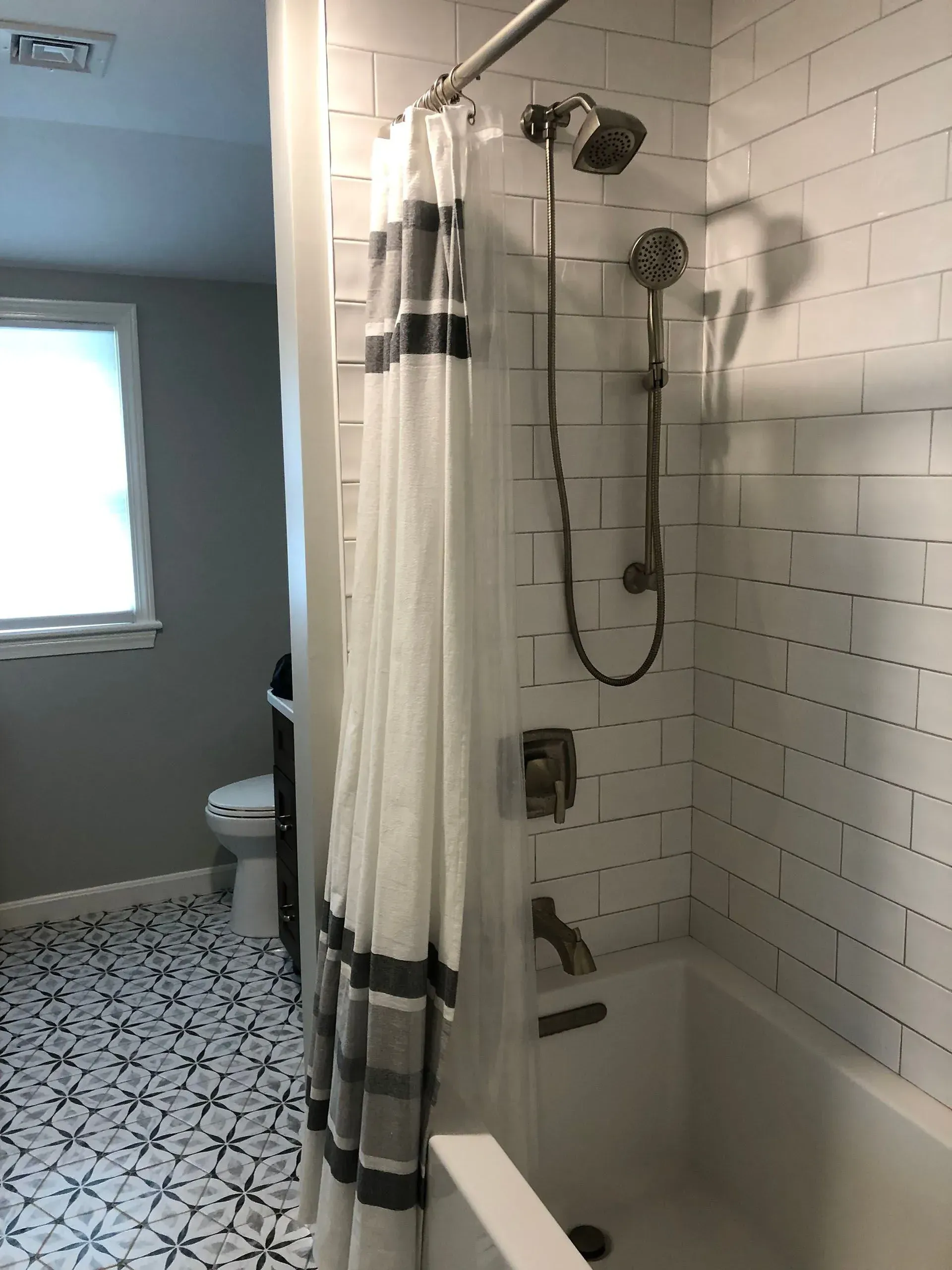 Bathroom with white subway tile, a bathtub, and a patterned floor.