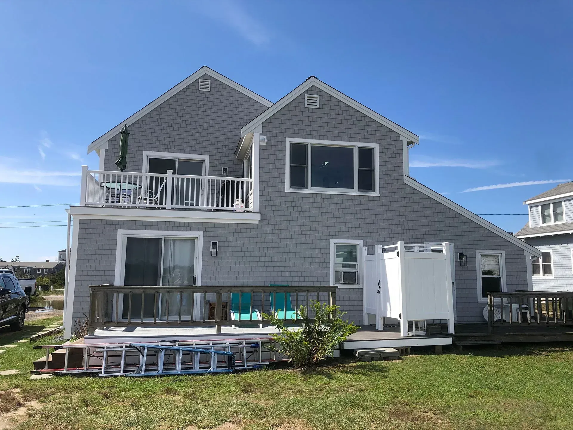 Gray shingled beach house with decks and a blue sky.