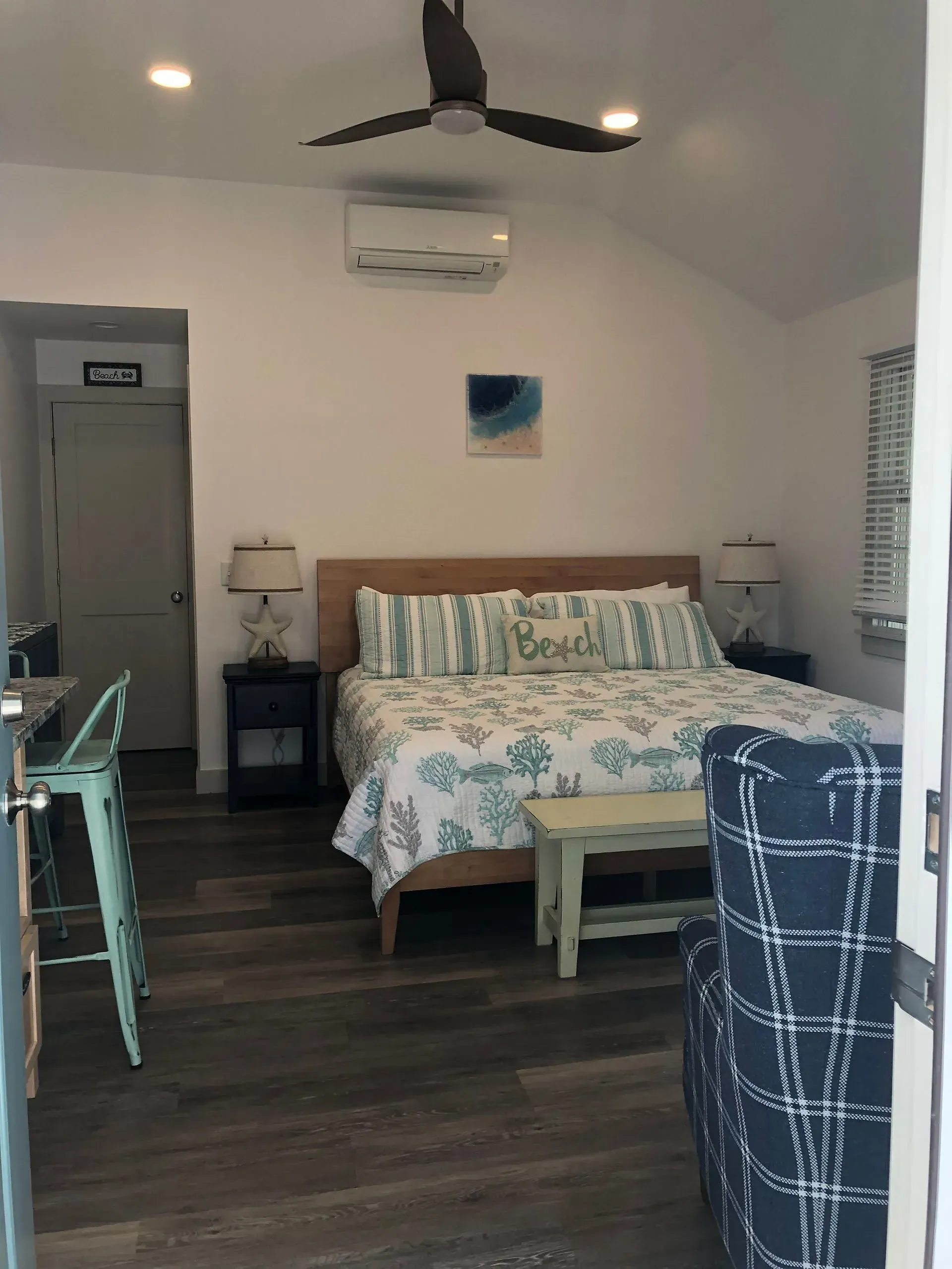 Bedroom interior with a queen-sized bed, blue and white decor, and a small sitting area.