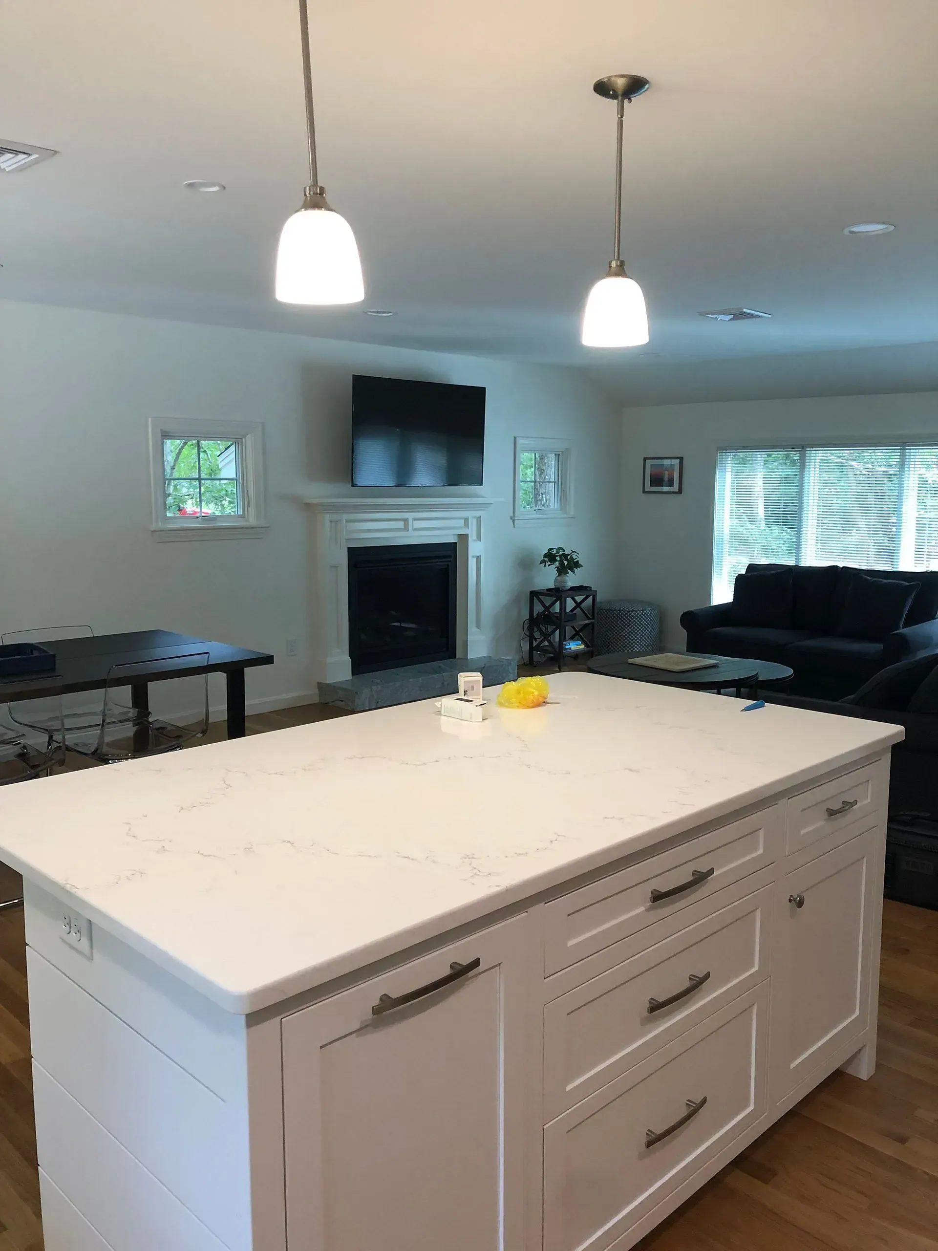 Kitchen island with two pendant lights, and a living room in the background.