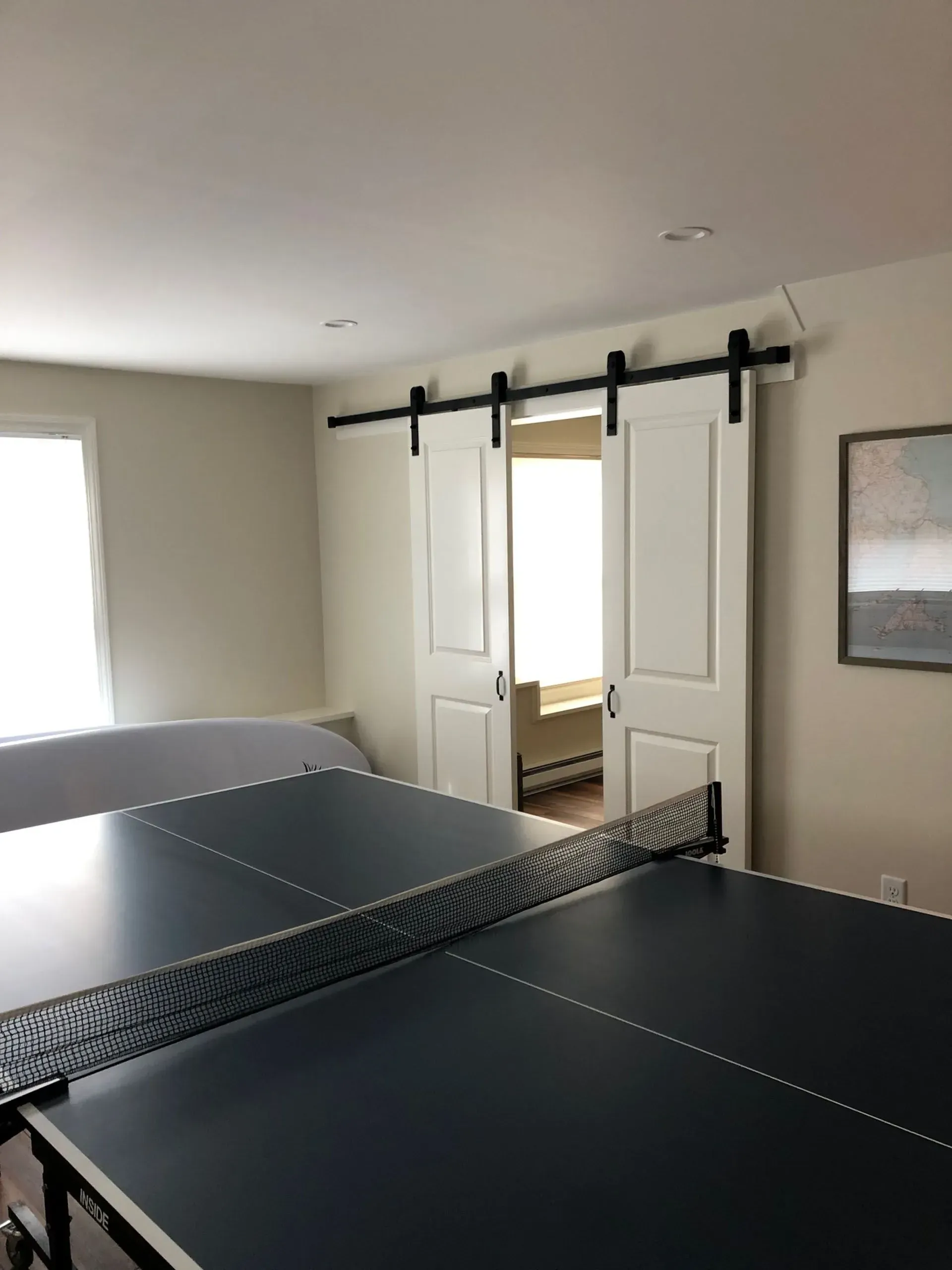 Ping pong table in a room with white sliding doors and a window.