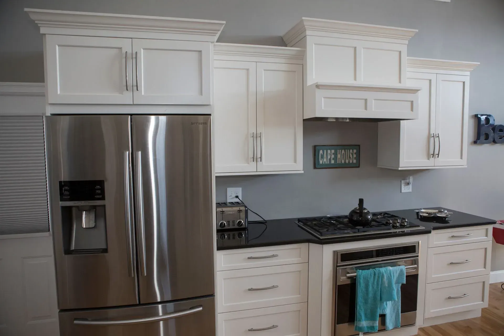 White kitchen cabinets with black countertops and stainless steel appliances.