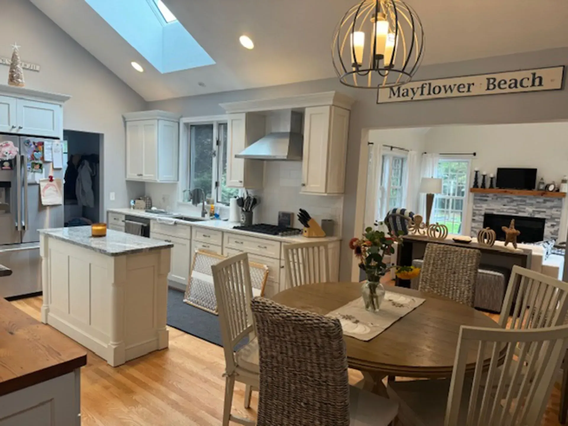Spacious kitchen with island, white cabinets, round table, chairs, and skylight. 