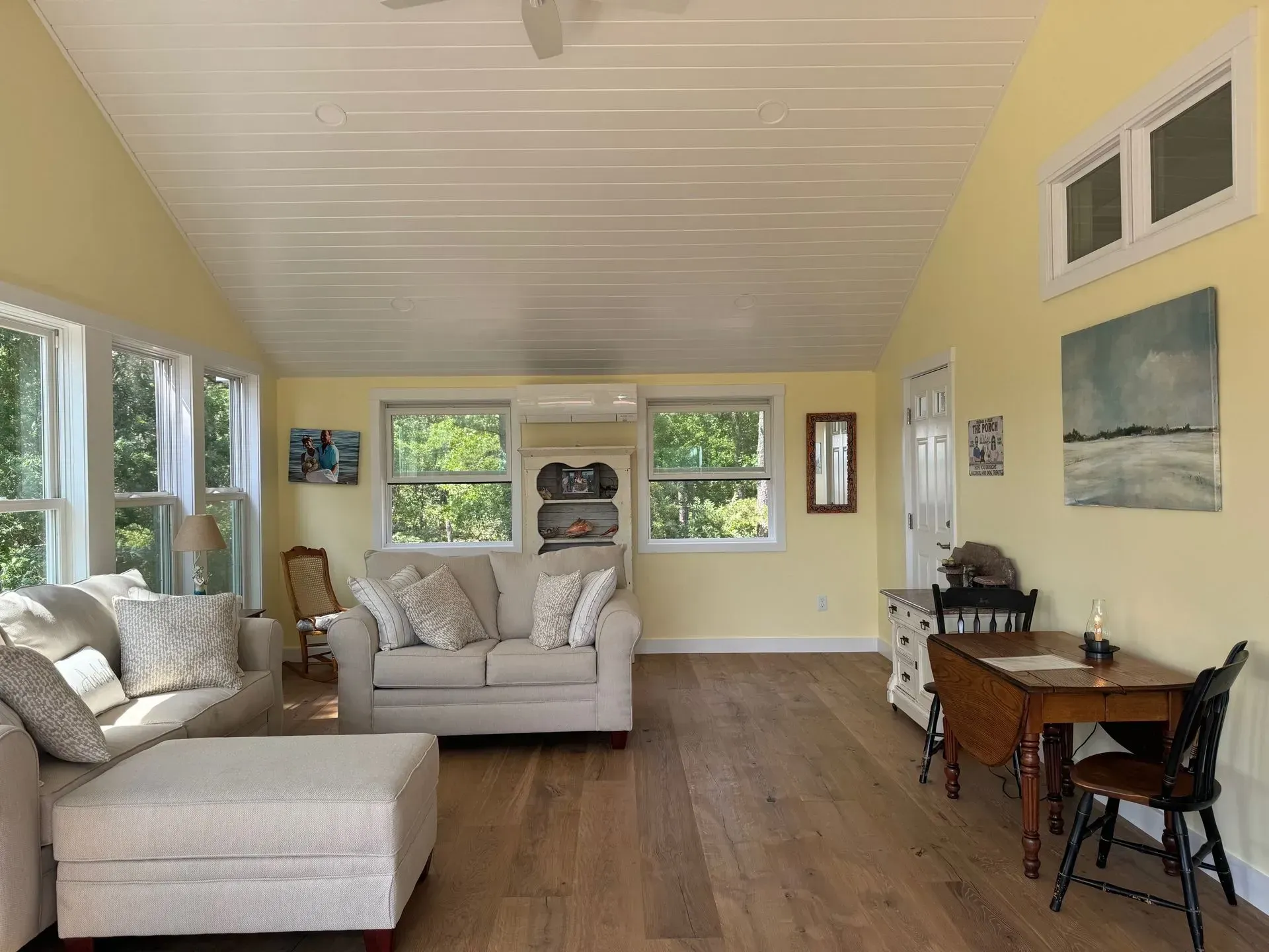 Bright living room with light yellow walls, wood floor, white ceiling, and a seating area.