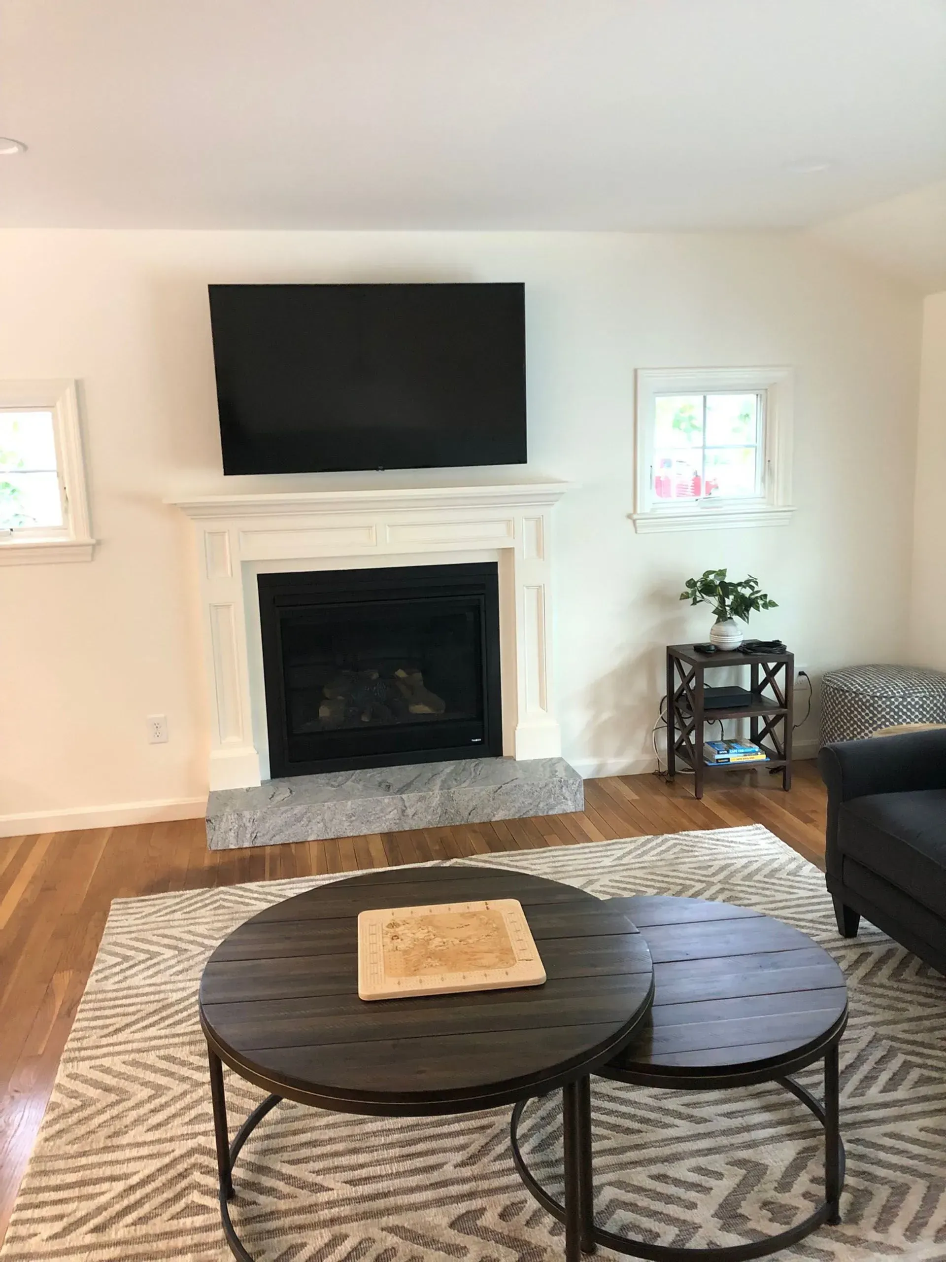 Living room with a fireplace, TV, and two round coffee tables on a patterned rug.